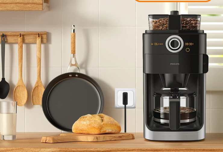 una presa smart in cucina tra una padella, il pane e una caffettiera