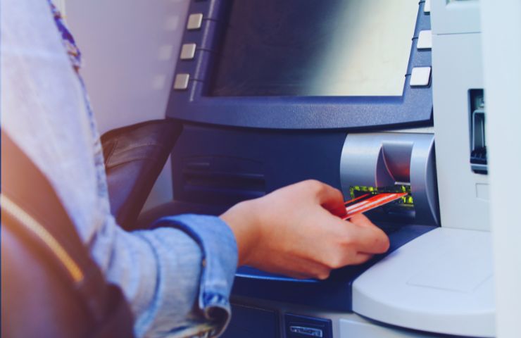 persona che inserisce una carta di credito in uno sportello ATM 