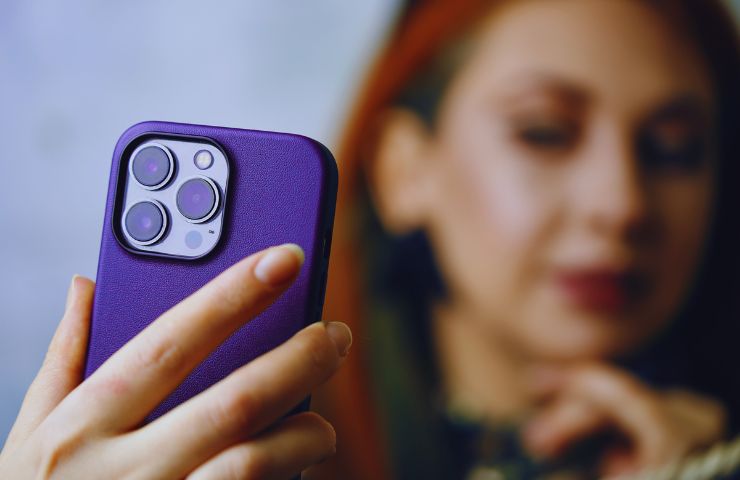 ragazza dai capelli rossi con volto sfocato si fa un selfie con un iPhone