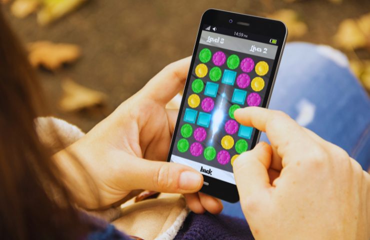 persona che gioca con lo smartphone a un gioco simile a Candy Crush 