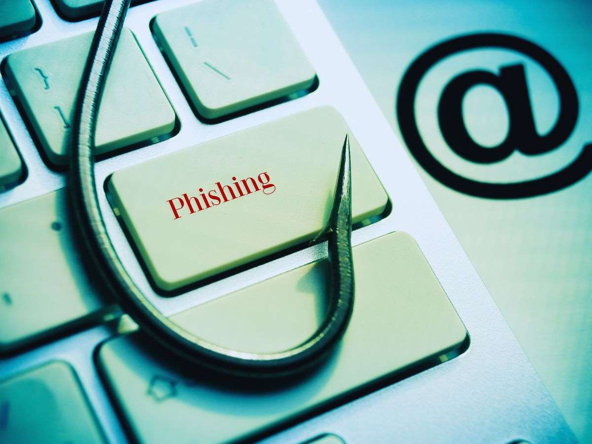 zoom su una tastiera di un laptop con un tasto con scritto "Phishing", un amo appoggiato sopra e una chiocciola di fianco