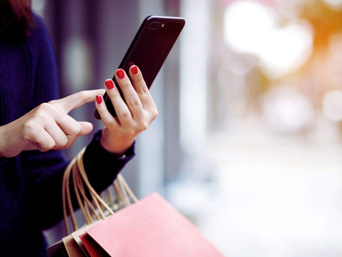 una ragazza con delle buste e lo smartphone