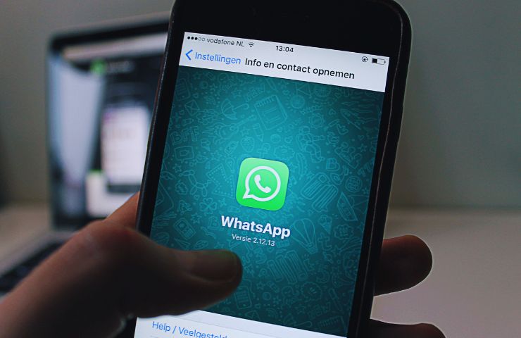 persona che tiene in mano uno smartphone con schermata WhatsApp